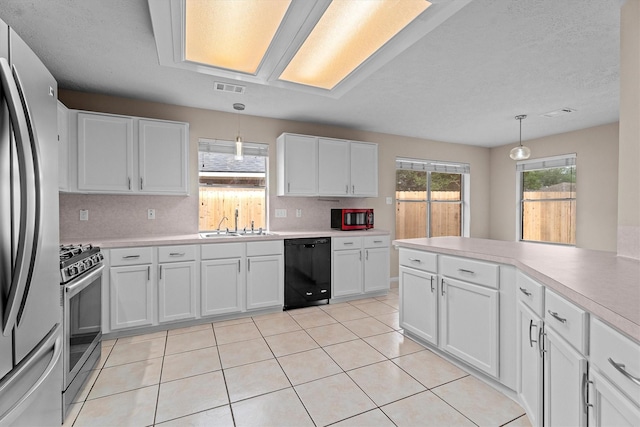 1635 Ashton Village Dr, Spring, TX 77386 - kitchen with visible vents, light countertops, white cabinets, appliances with stainless steel finishes, and decorative light fixtures