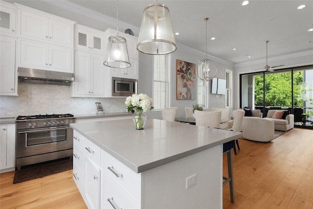6113 Nicholas Grove Pl, Houston, TX 77055 - kitchen featuring crown molding, appliances with stainless steel finishes, a center island, open floor plan, and under cabinet range hood