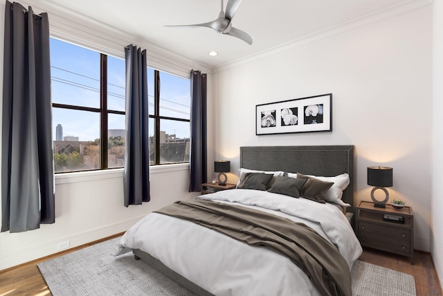 bedroom featuring ceiling fan, baseboards, ornamental molding, and wood finished floors