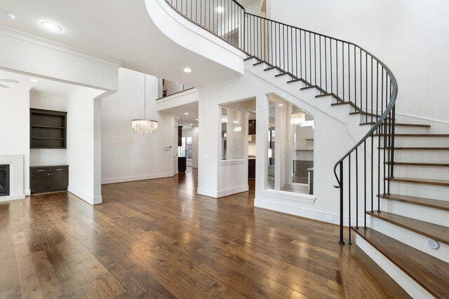 6011 Burgoyne Rd Unit A, Houston, TX 77057 - unfurnished living room with a chandelier, stairs, a glass covered fireplace, wood finished floors, and ornamental molding