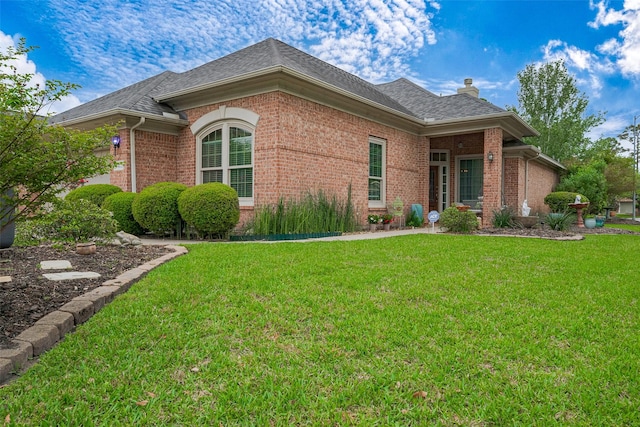 view of home's exterior featuring a chimney, a yard, and brick siding