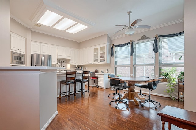 kitchen with a kitchen breakfast bar, appliances with stainless steel finishes, white cabinetry, and glass insert cabinets