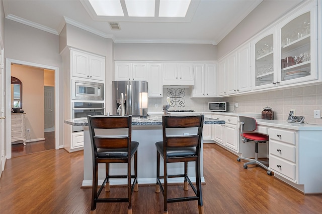 kitchen featuring visible vents, glass insert cabinets, white cabinetry, appliances with stainless steel finishes, and backsplash