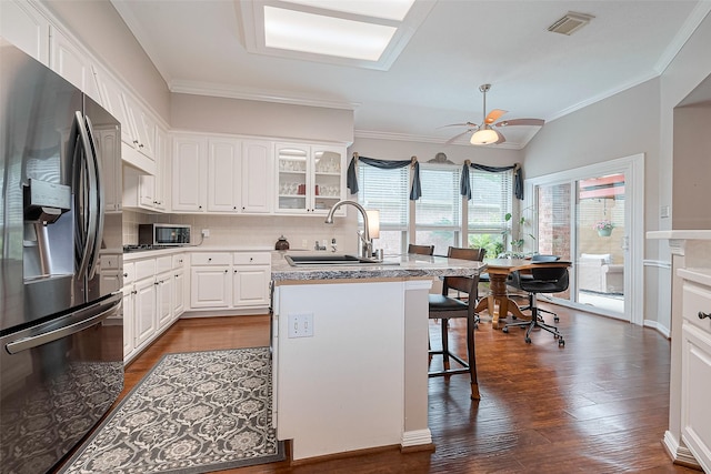 kitchen with stainless steel refrigerator with ice dispenser, a sink, a breakfast bar area, and dark wood-type flooring