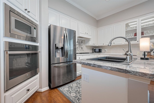 kitchen with a sink, ornamental molding, stainless steel appliances, white cabinetry, and dark wood-type flooring