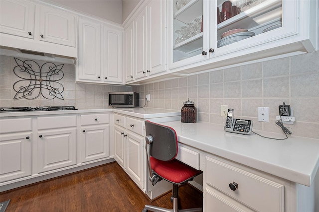 home office featuring built in study area, dark wood finished floors, and visible vents