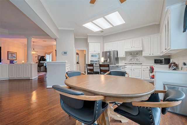 dining room with ornate columns, dark wood finished floors, and crown molding