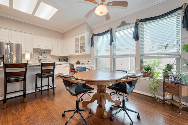 dining space with baseboards, ornamental molding, dark wood finished floors, and a ceiling fan