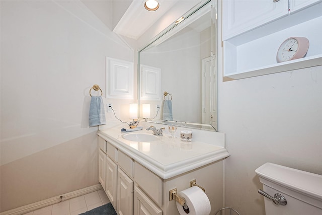 half bathroom with vanity, baseboards, tile patterned floors, and toilet