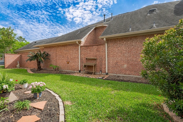 back of house featuring brick siding, roof with shingles, and a yard