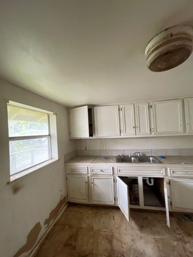 kitchen with white cabinets, tile countertops, open shelves, and a sink