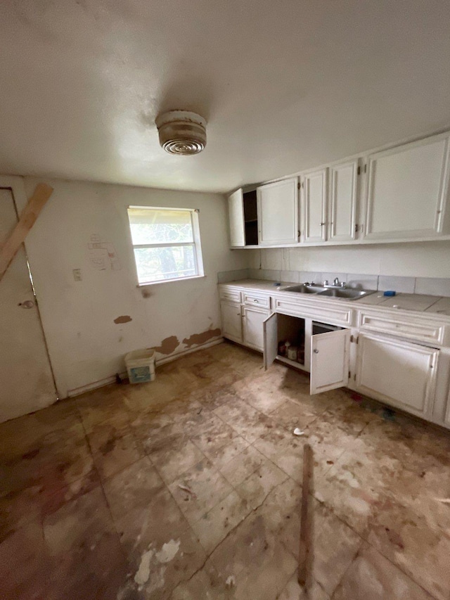 kitchen featuring light countertops, open shelves, white cabinetry, and a sink