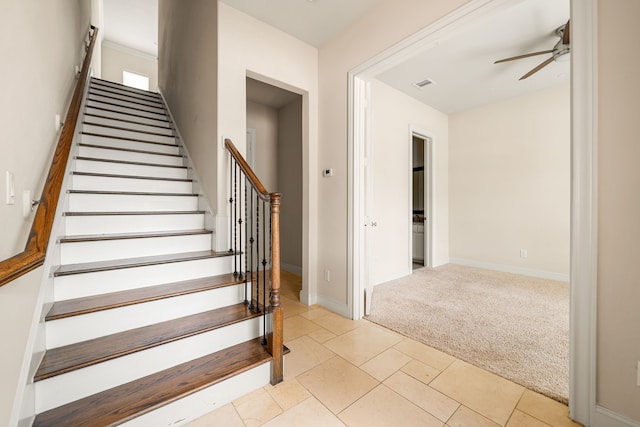 stairs with a ceiling fan, visible vents, tile patterned flooring, baseboards, and carpet flooring