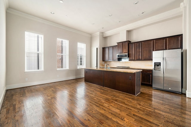 kitchen featuring ornamental molding, a kitchen island with sink, dark brown cabinets, a sink, and appliances with stainless steel finishes