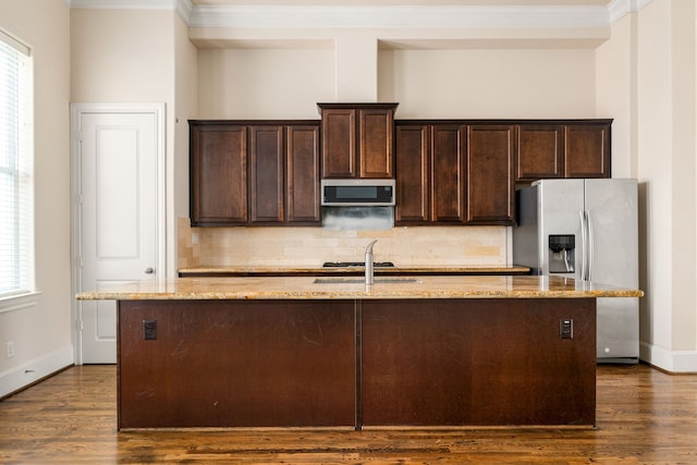 kitchen with a center island with sink, decorative backsplash, stainless steel appliances, and dark wood-style floors