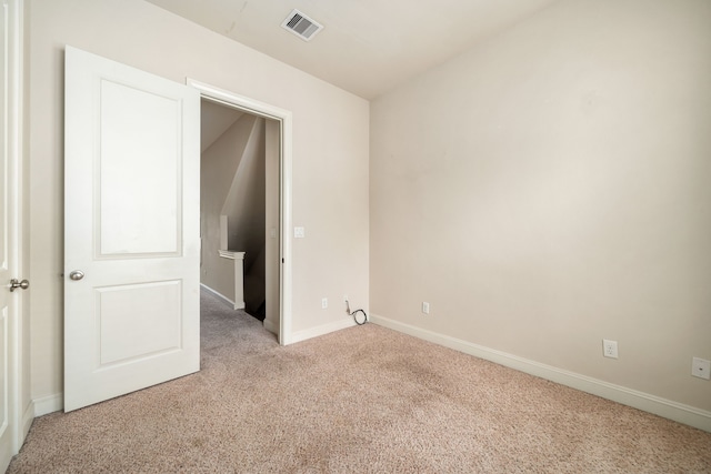 unfurnished room featuring baseboards, light colored carpet, and visible vents