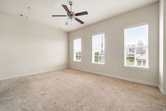 carpeted spare room with baseboards, visible vents, and ceiling fan