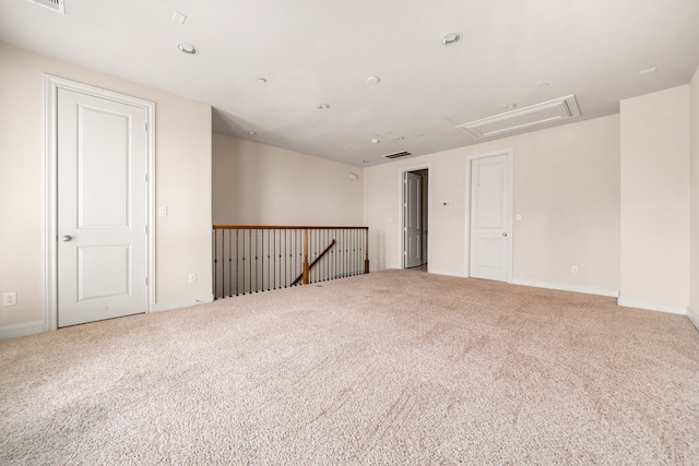 carpeted spare room with baseboards, attic access, and visible vents