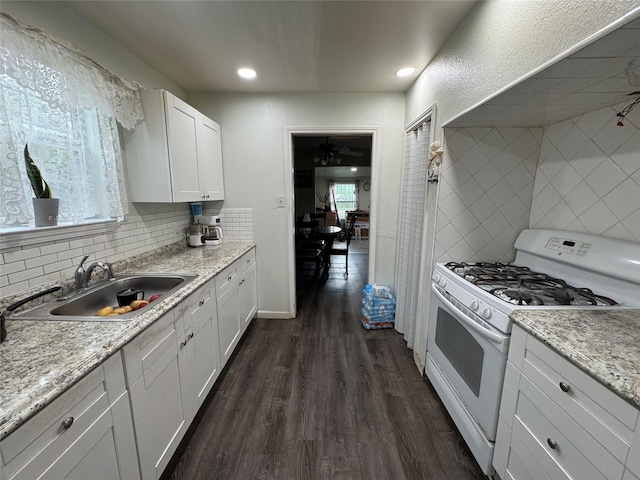 5526 Bunte St, Houston, TX 77026 - kitchen with a sink, dark wood-style floors, white cabinetry, white gas range oven, and backsplash