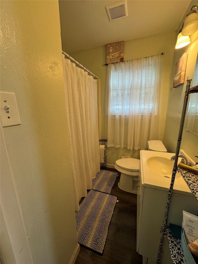 5526 Bunte St, Houston, TX 77026 - full bath with visible vents, vanity, curtained shower, wood finished floors, and toilet
