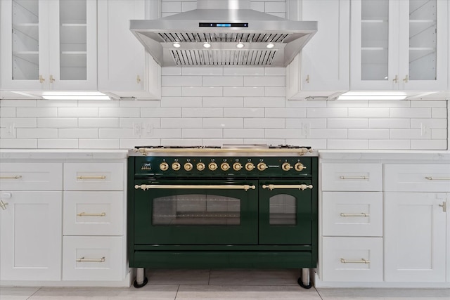 2611 Teague Rd, Houston, TX 77080 - kitchen with range with two ovens, decorative backsplash, white cabinets, and wall chimney exhaust hood