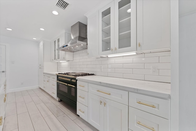 2611 Teague Rd, Houston, TX 77080 - kitchen with double oven range, visible vents, white cabinetry, wall chimney range hood, and tasteful backsplash