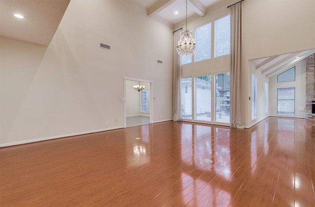 714 Last Arrow Dr, Houston, TX 77079 - unfurnished living room with a chandelier, beam ceiling, a towering ceiling, wood finished floors, and baseboards