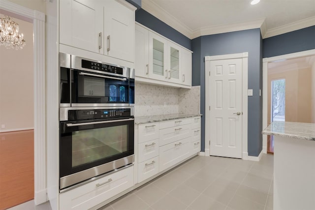 714 Last Arrow Dr, Houston, TX 77079 - kitchen with stainless steel double oven, white cabinets, light stone counters, glass insert cabinets, and a chandelier