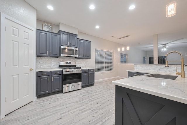 kitchen featuring decorative backsplash, a ceiling fan, a sink, decorative light fixtures, and stainless steel appliances