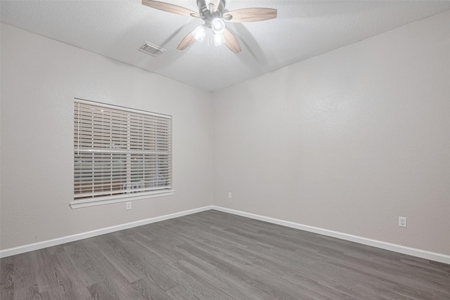 empty room with a ceiling fan, baseboards, visible vents, and dark wood-style floors