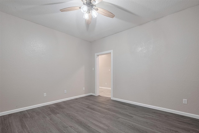 spare room with ceiling fan, baseboards, and dark wood-type flooring