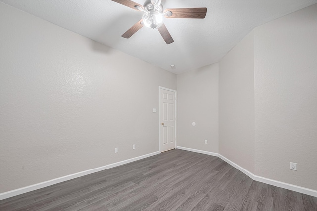 spare room featuring baseboards, dark wood-style flooring, and ceiling fan