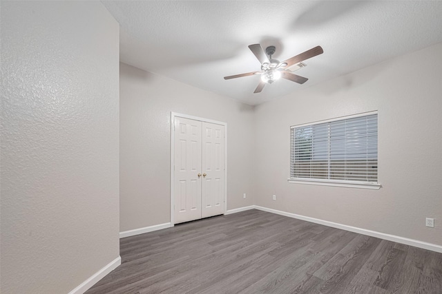 unfurnished room with baseboards, a ceiling fan, and dark wood-style floors