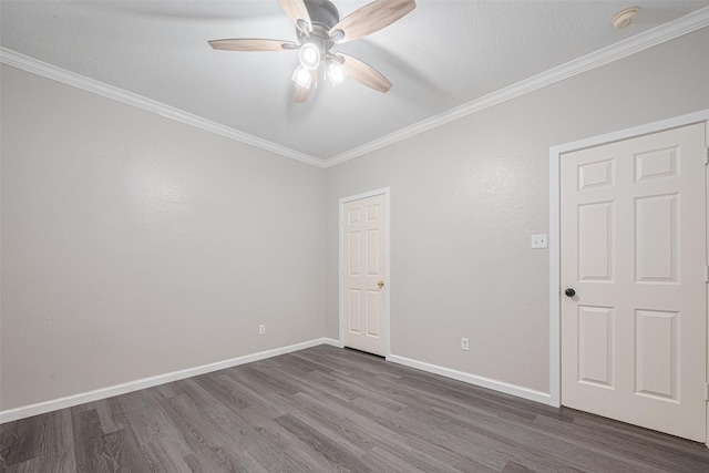 empty room featuring crown molding, a ceiling fan, dark wood finished floors, and baseboards