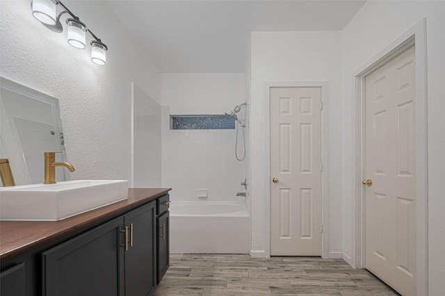 bathroom featuring vanity, bathing tub / shower combination, and wood finished floors