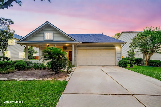 view of front of home featuring concrete driveway, a yard, a porch, and a garage