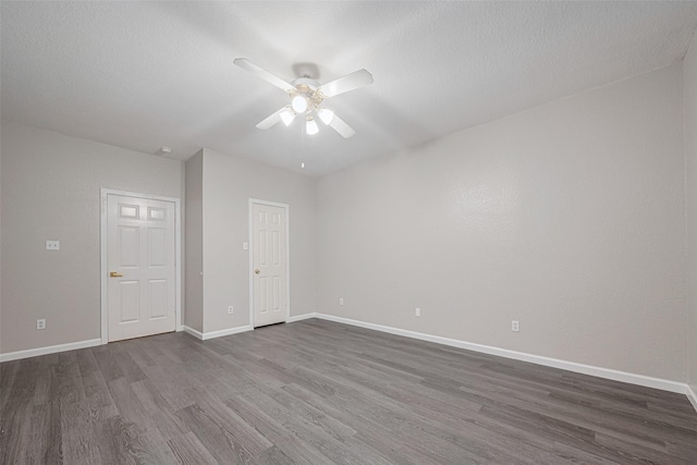 unfurnished room featuring a ceiling fan, baseboards, and dark wood-style floors
