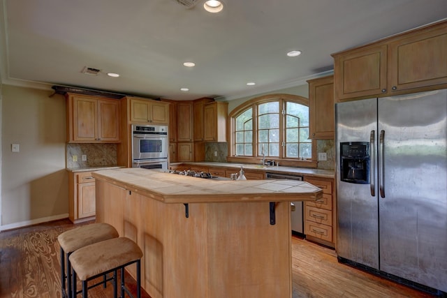 708 4th St, Sealy, TX 77474 - kitchen with appliances with stainless steel finishes, tile counters, a center island, a breakfast bar area, and recessed lighting