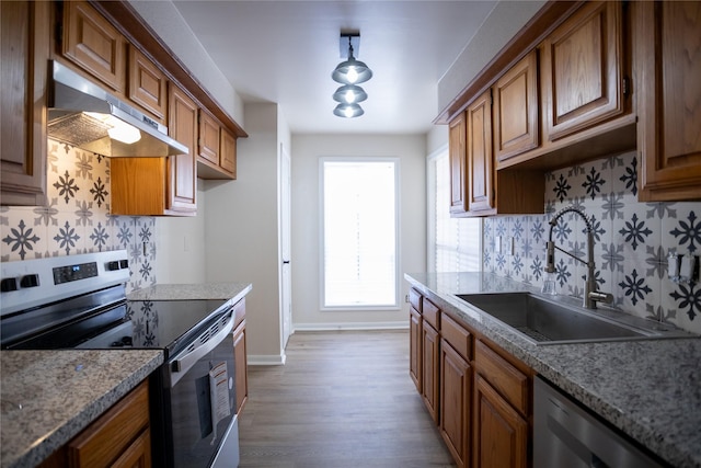 1311 Antoine Dr Unit 245, Houston, TX 77055 - kitchen with a sink, brown cabinetry, stainless steel appliances, tasteful backsplash, and under cabinet range hood
