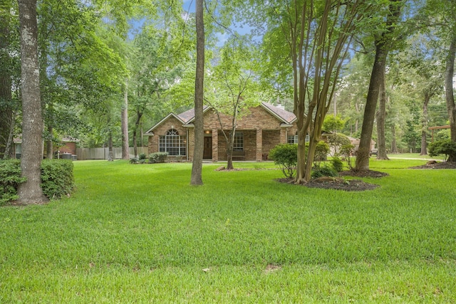 view of front of property featuring brick siding, fence, and a front yard