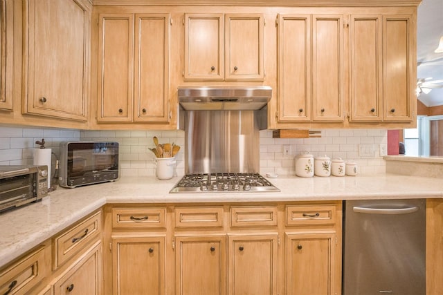 kitchen with backsplash, appliances with stainless steel finishes, light countertops, a toaster, and under cabinet range hood
