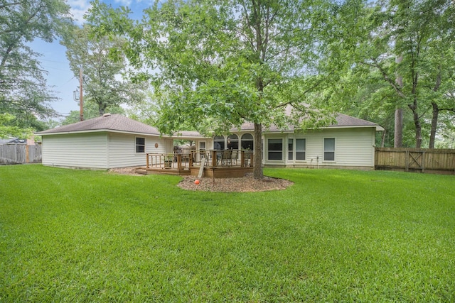 rear view of house with a lawn, a wooden deck, and a fenced backyard
