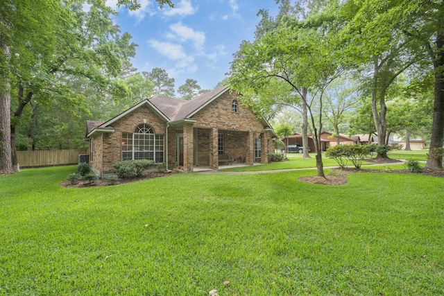 exterior space with fence, a shingled roof, a front lawn, and brick siding