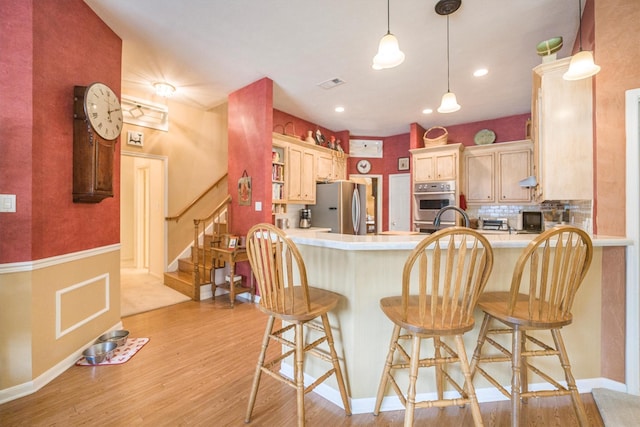 kitchen with a peninsula, stainless steel appliances, light wood finished floors, and visible vents