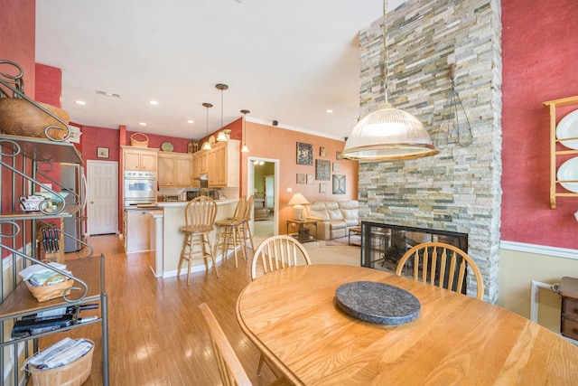 dining space with light wood-style floors, recessed lighting, visible vents, and a stone fireplace