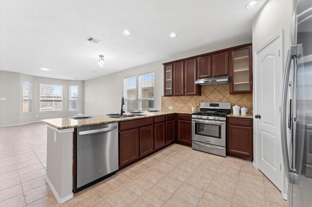 kitchen with visible vents, appliances with stainless steel finishes, a sink, a peninsula, and under cabinet range hood