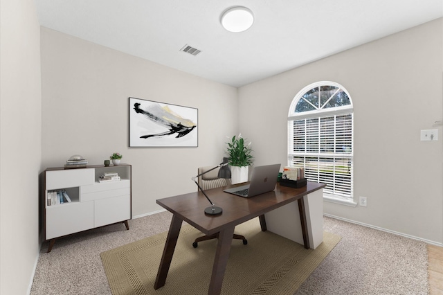 office with baseboards, visible vents, and light carpet