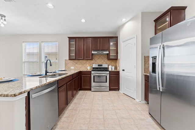 kitchen featuring decorative backsplash, appliances with stainless steel finishes, a sink, a peninsula, and under cabinet range hood