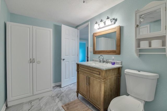 bathroom with vanity, a textured ceiling, marble finish floor, and toilet