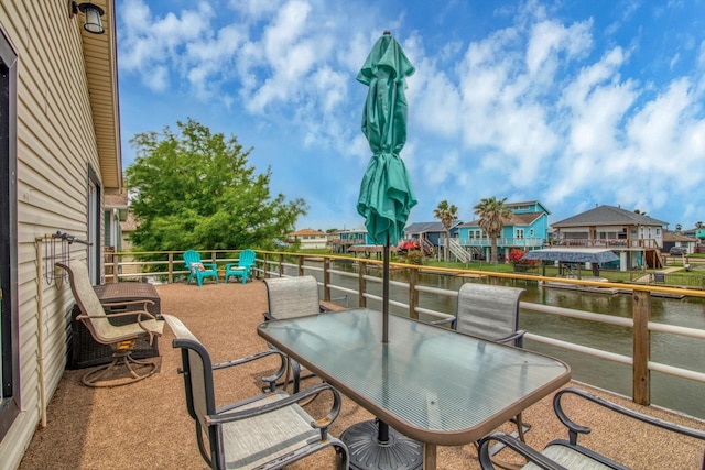 view of patio with outdoor dining area, a water view, and a residential view
